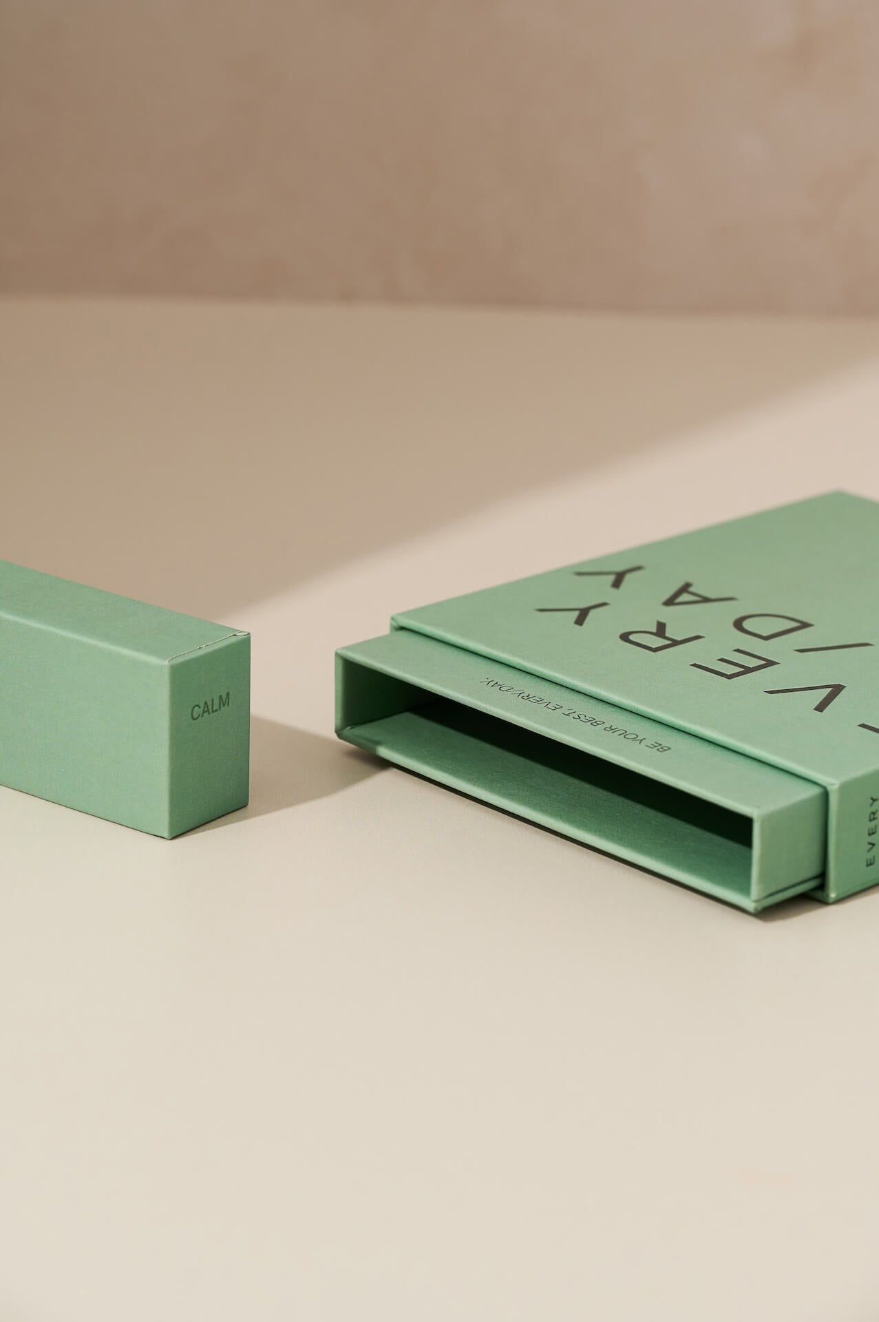 Everyday Supplements sage green packaging lying face up on a flat surface, with the matching lid positioned upright next to it, highlighting the minimal, eco-friendly design and thoughtful, user-friendly packaging.