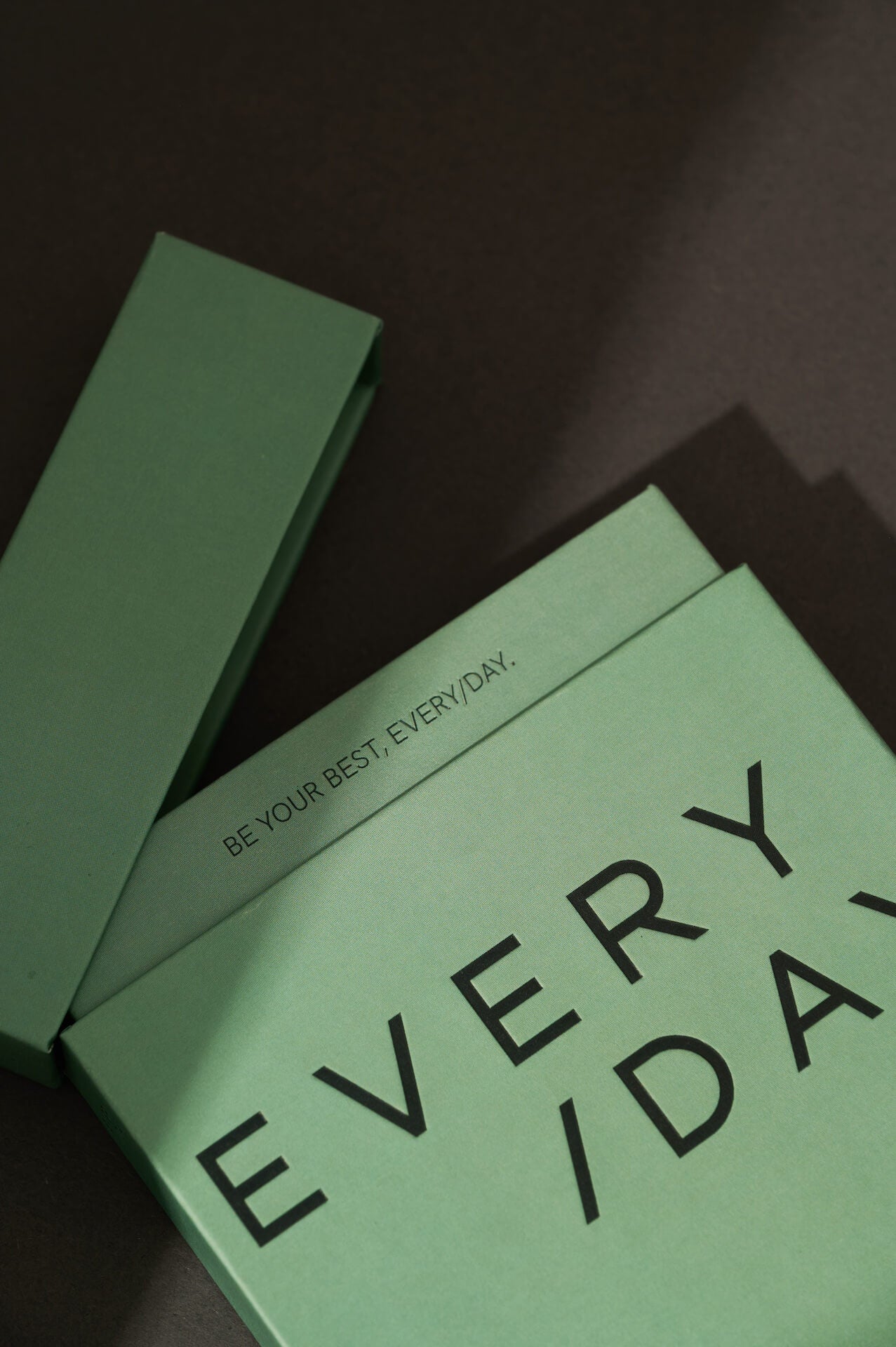 Close-up of Everyday Supplements sleek sage green packaging, featuring the brand name in minimalist white font and the tagline 'be your best every/day', a reminder to prioritise wellbeing every single day.