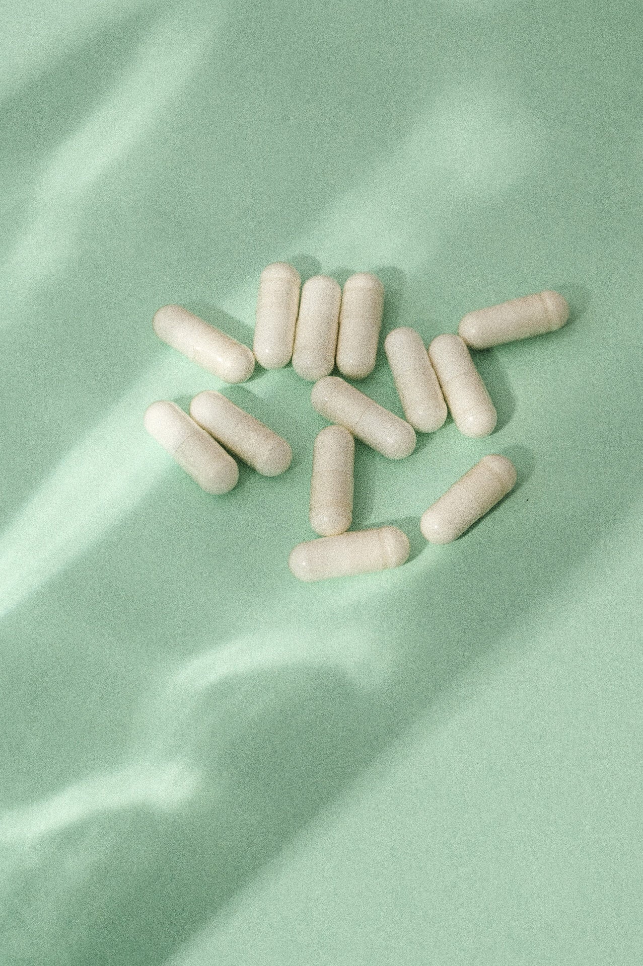 Everyday Supplements’ L-Theanine capsules photographed on a soft green backdrop, illuminated by gentle lighting to highlight the purity and simplicity of the product